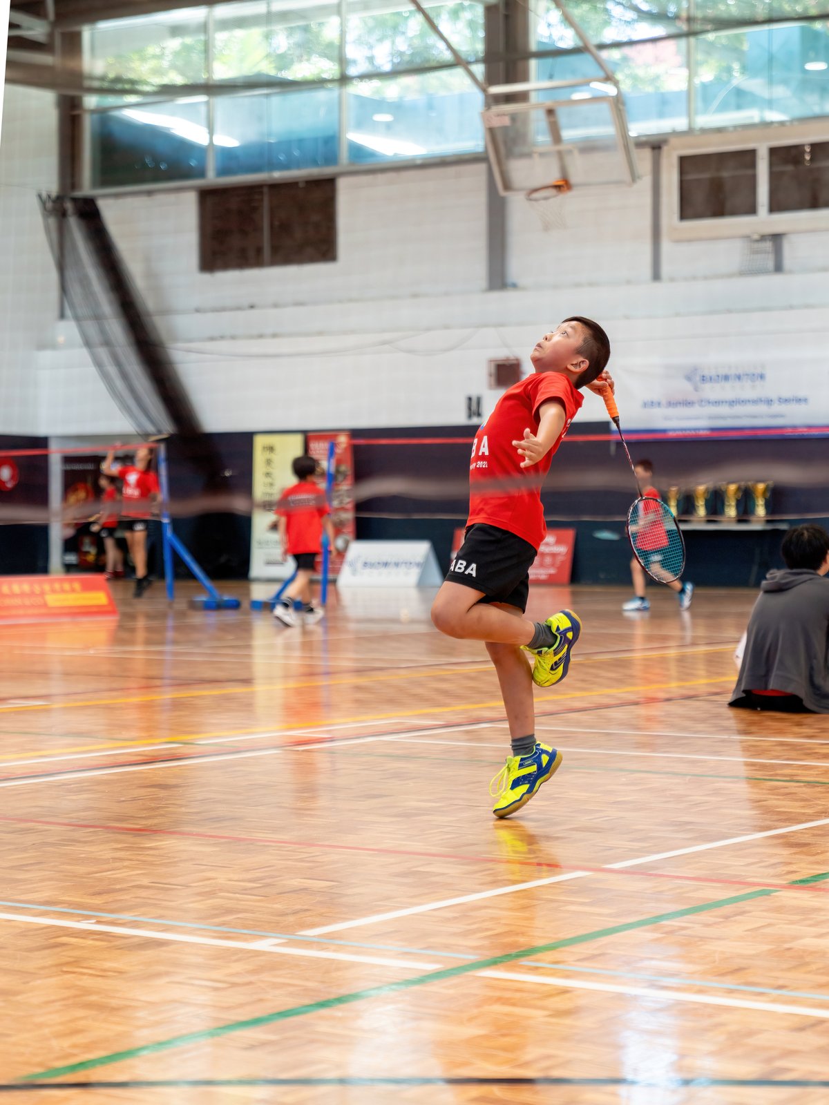 An ABA junior player mid-smash at a tournament